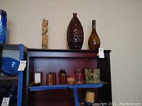 Wide shot showing the lot of vases, carved statue, candle holders, and decorative items on shelves