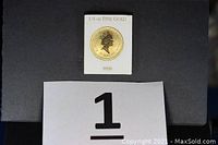 White protective card printed '1/4 oz Fine Gold' on top and '9999' at bottom, housing gold coin, displayed on black background with lot number card