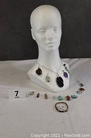 Full view of mannequin bust displaying 5 of the pendants on the necklace, additional pendants and sterling silver bracelet with turquoise stones laid out below