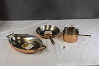 Three-piece Revere Ware cookware set with copper bottoms displayed on white cloth, showing entire set arrangement.