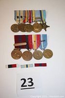 Two racks of nine U.S. military medals and three ribbon bars displayed on white surface.