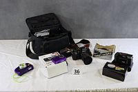 Overview of all cameras with camera bag and boxes displayed on table.