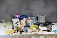 Full view of assorted items including purses, cocktail glasses and pitcher, pillow, scarves, sunglasses, and stationery items.