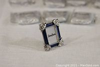 Mini picture frame front angled view showing silver floral corners and blue border.