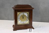 Front view of the wooden mantel clock showing the overall case and clock face, with the seller's lot number in front