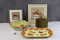 Photo showing large rectangular platter, square platter, bowl, moss-covered fruit box, and two framed fruit-themed prints arranged together