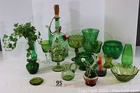 Photo showing entire lot of green glassware including wine carafe with ice compartment, pitchers, vases, bowls, and covered dish.