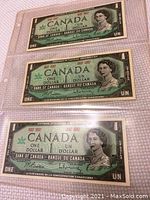 Front view of three uncirculated Canada Centennial one dollar bills showing Queen Elizabeth II portrait and denomination details.