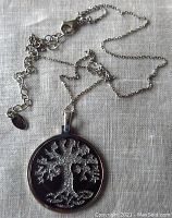Full view of the tree of life pendant and chain on fabric background showing pendant details.