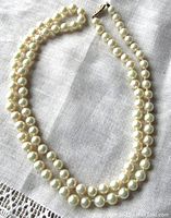 Full view of two-strand pearl necklace laid on fabric