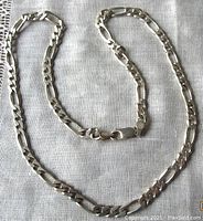 Full view of the vintage sterling silver Figaro style chain laid on a linen surface.