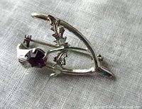 Front view of the sterling silver Celtic horseshoe pin with purple rhinestone and detailed leaves.