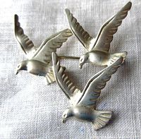Front view of the sterling silver bird brooch showing three birds in flight positioned on a fabric background.