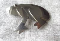 Front view of the vintage silver frog brooch showing the smooth polished surface, cut-out leg details, and overall shape.