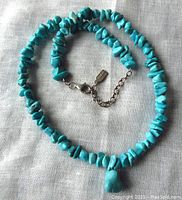 Full view of turquoise nugget necklace with central pendant on cloth background.