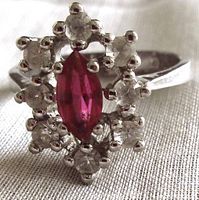 Front close-up of the ring showing marquise-shaped deep pink center stone surrounded by clear stones in prong setting.
