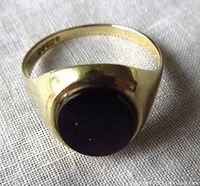 Top view of the vintage black onyx cabochon ring showing gold band and oval stone.