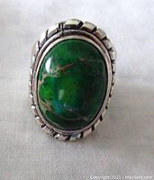 Close-up front view showing the green turquoise stone and detailed silver double frame setting on the ring.