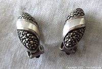 Front view of both earrings showing mother of pearl central band and marcasite stone details on sterling silver base.