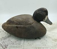 Side profile of vintage hand carved wooden duck decoy showing wear and paint detail