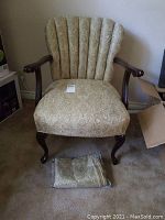 Full front view of vintage arm chair with patterned upholstery and wooden arms and legs, spare fabric roll placed on floor in front.
