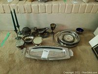 Full lot arranged on carpet featuring all silver plate items including candle sticks, lidded dish, trays, goblet, and caviar dish.