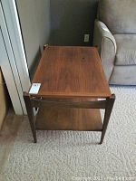 Front view of teak side table showing rectangular top and lower shelf