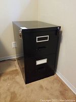 Front view of black metal two-drawer file cabinet with keys inserted in lock