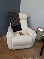 White electric La-Z-Boy recliner chair with plaid throw placed on the left armrest, photographed from the front showing full chair.