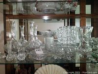 Wide shot showing crystal vases, decanters, ashtray, and footed bowl inside display cabinet