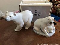 Two Lladro porcelain polar bear figurines shown together with original box in the background.