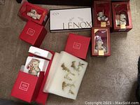 Photo showing nine Lenox branded boxes containing Christmas collectible ceramics and glass figures including bears and Santa Claus, plus gold-tone angel ornaments in foam.