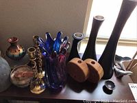 Overview of brass candlesticks, art glass vase, wooden candleholders and vases on shelf