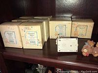 Cherished Teddies boxes showing brand labels and floral design on packaging with several boxes stacked on a shelf.