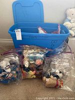 Blue storage tub containing multiple clear plastic bags labeled with TY production years and containing assorted TY Beanie Babies and Broncos Bears plush toys.