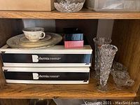 Wood shelf holding porcelain plates, cup with rose pattern, two Bohemia crystal boxes.