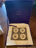 Purple velvet box with satin lining containing four Wedgwood Federal City decorative plates with historic building prints.