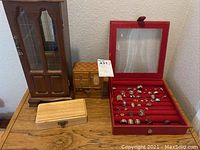 Full view of four jewelry boxes on a wooden surface including a red jewelry box filled with rings and three additional wooden boxes of varying size and wood finish.