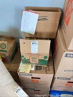 Three stacked boxes labeled as box 479, one box with a list taped on the outside, containing hardcover books.