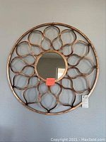Front view of round metal framed mirror with decorative pattern and reflective surface