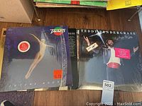 Two LP records visible: Tavares 'Future Bound' and Teddy Pendergrass 'This One Is For You' with other LPs stacked behind.