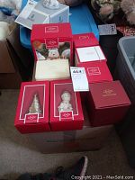 Eight Lenox figurines and ornaments displayed on and around a box, all in original packaging with red Lenox boxes visible.