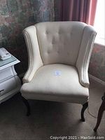 Front view showing button-tufted backrest, seat cushion and front cabriole legs