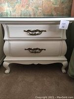 Front view of white painted nightstand showing two drawers and brass hardware