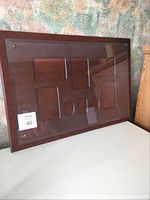 Front view of Bombay Company wooden picture frame with multiple photo openings and brass corner accents, resting against a wall.