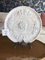Front view of large decorative plate with floral embossed details on ornate metal stand