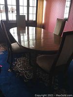 Oval dining table with six chairs arranged around, showing table top and chairs