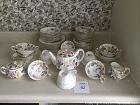 Full assortment: two stacks of bowls at back, teapot and lid centre, sugar bowl left front, creamer and cups and saucers front right.