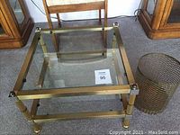 Square brass frame side table with two glass shelves shown from top angle, clear glass shelves, brass frame with minor scratches.