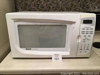Front view of a white Kenmore microwave oven on a kitchen counter, showing the door with a large window and a handle.